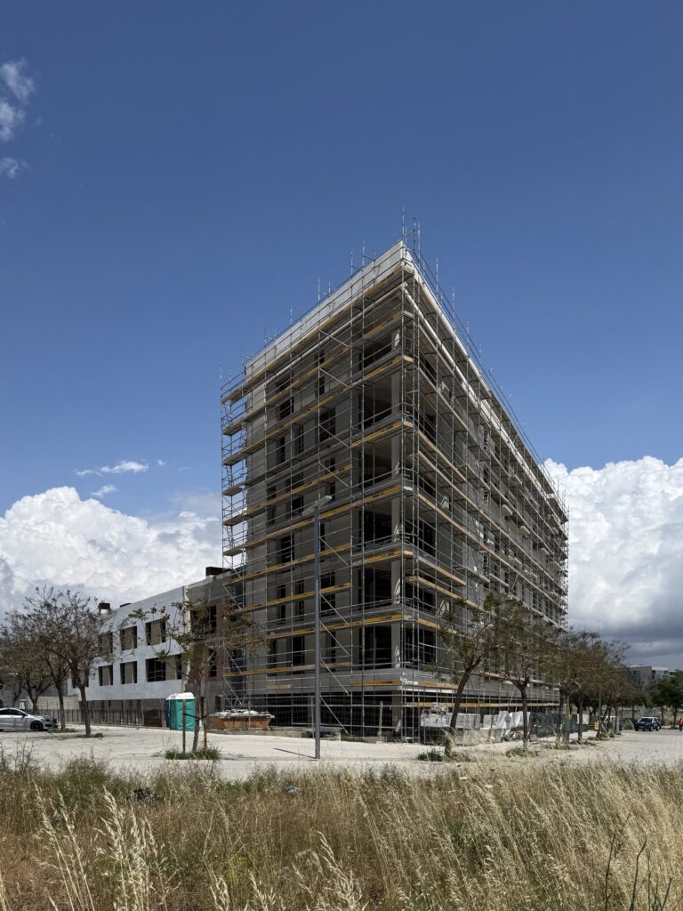 Residencia para mayores en construcción, con fachada cubierta por andamios, volumen principal de varias plantas y cielo despejado.